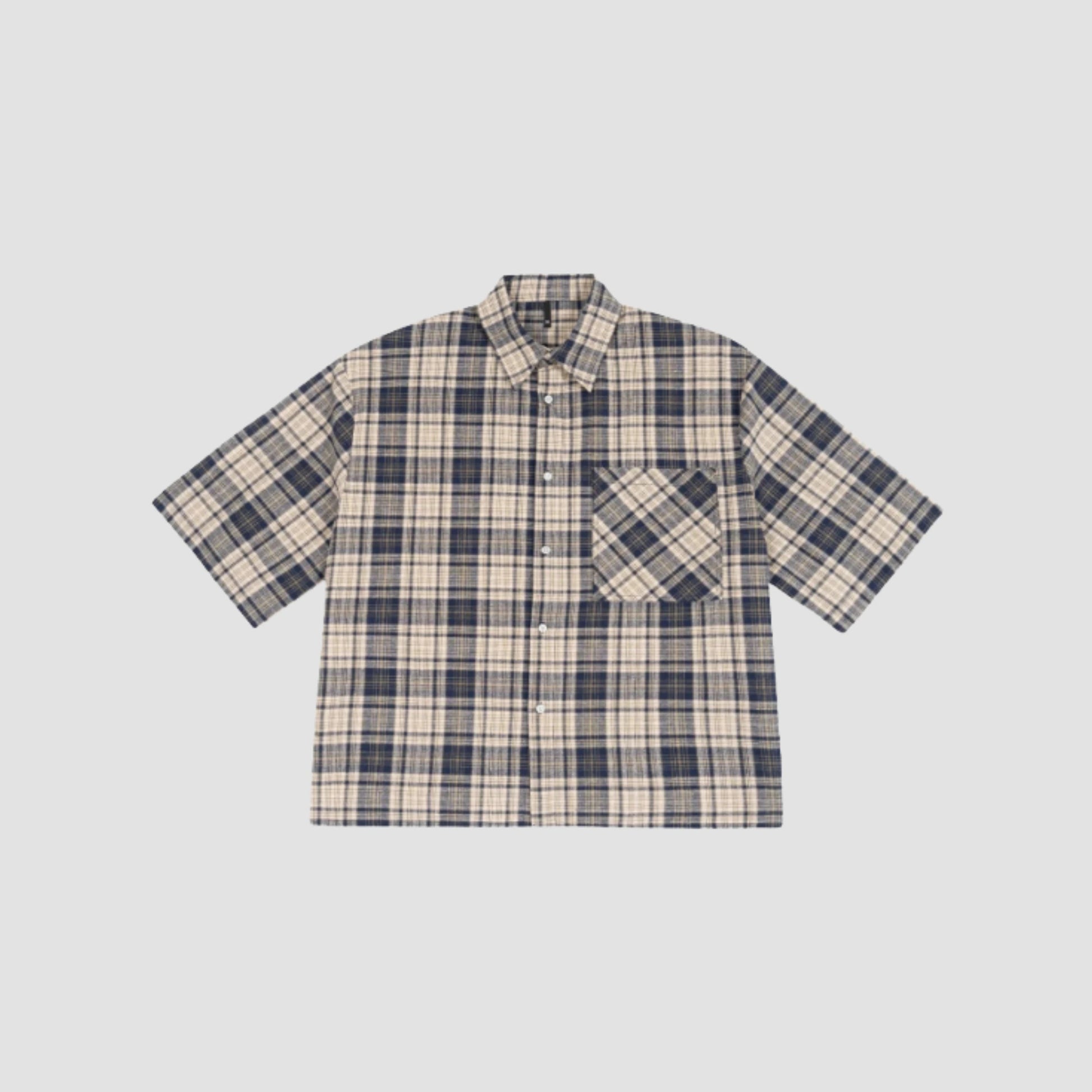 Une chemise bleue posée sur un fond blanc. Avec une poche sur le torse
